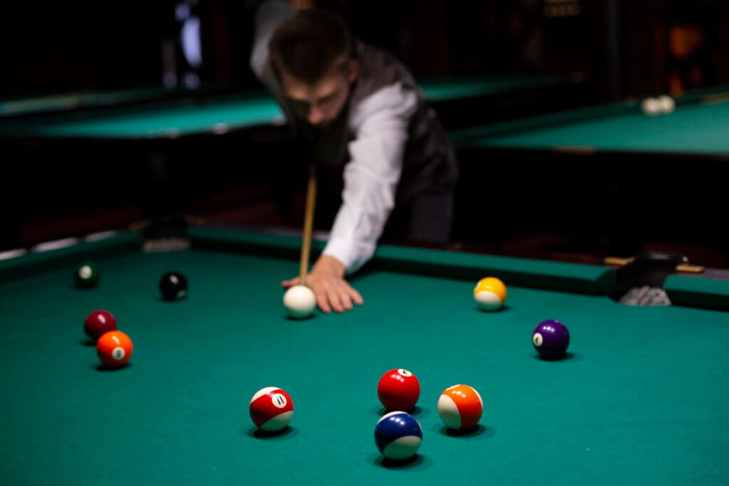 Player taking a shot on a pool table with colorful balls, showcasing precision on high-quality gorina speed cloth.
